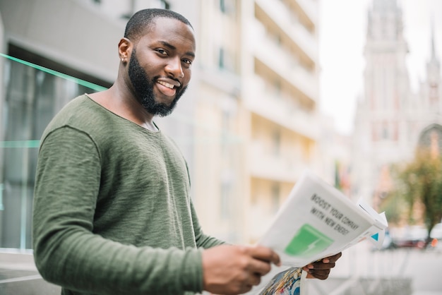 Free photo smiling man reading newspaper on street