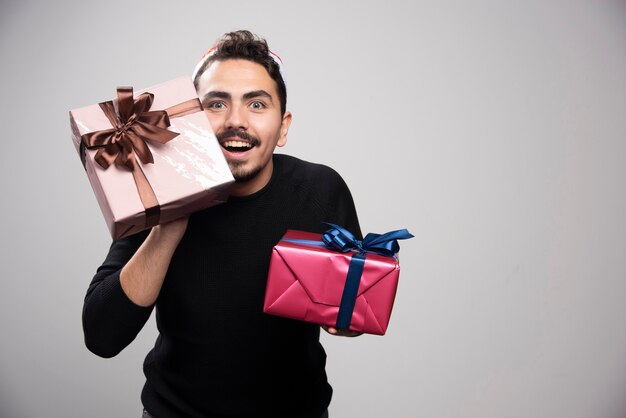 A smiling man in a Santa's hat holding a New Year's gifts .