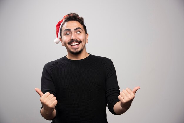 Smiling man in Santa's hat showing thumbs up.
