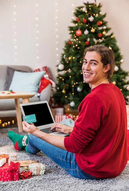 Smiling man shopping online with laptop 