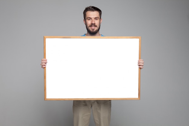 Smiling man showing empty white board