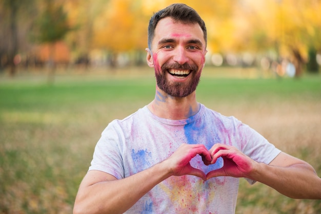 Uomo sorridente che mostra il segno di amore con le mani verniciate