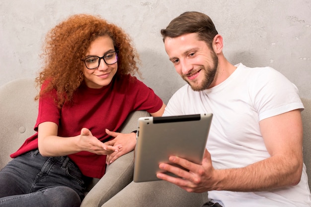 Free photo smiling man showing something to his friend on digital tablet