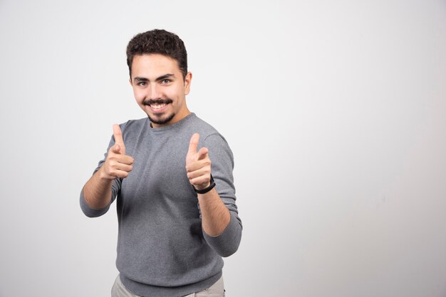 Smiling man showing thumbs up and looking at camera.