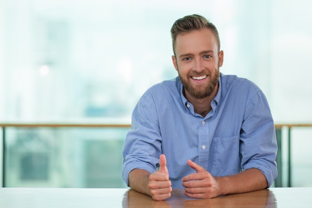 Smiling Man Sitting at Cafe Table and Gesturing