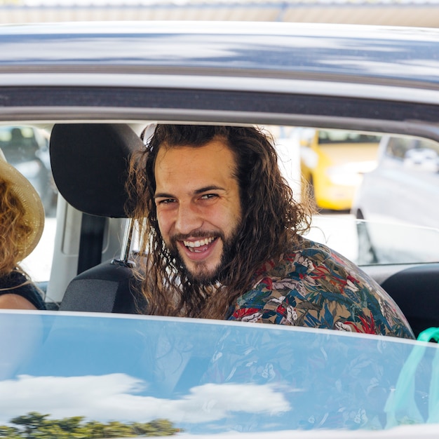 Uomo sorridente che si siede in automobile con la finestra aperta alla stazione di servizio