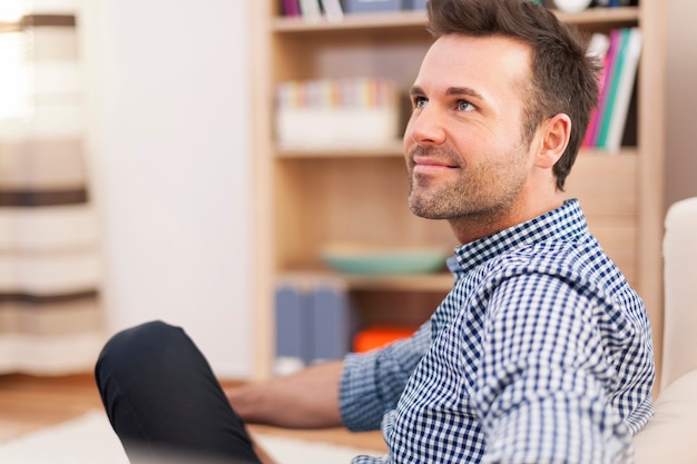 Smiling man sitting on sofa and looking away