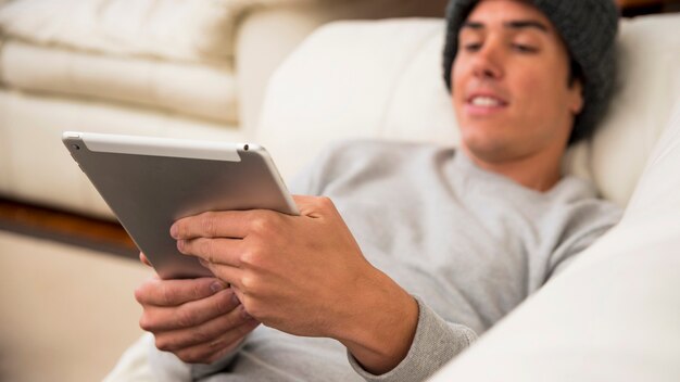Smiling man sitting on sofa looking at digital tablet