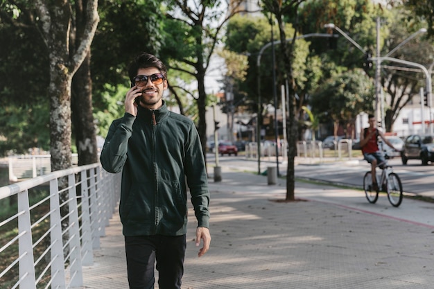 Free photo smiling man speaking on phone near fence