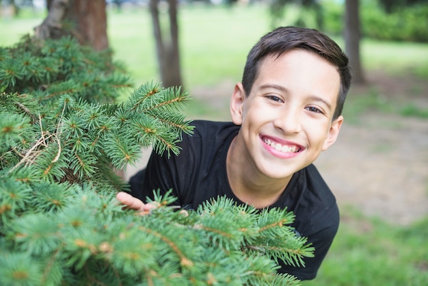 Free photo smiling man standing near the green tree spruce branches