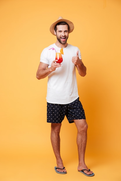 Smiling man in summer hat with cocktail looking camera