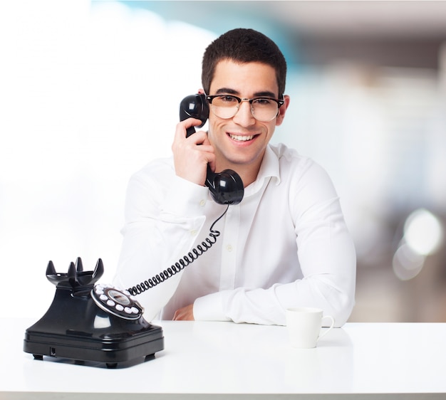 Uomo sorridente che comunica su un telefono nero