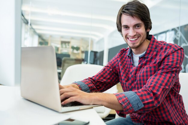 Smiling man typing on a laptop
