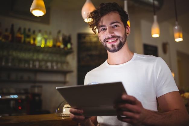 Smiling man using digital tablet in cafe