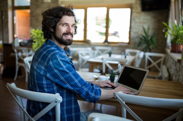 Free photo smiling man using laptop in coffee shop