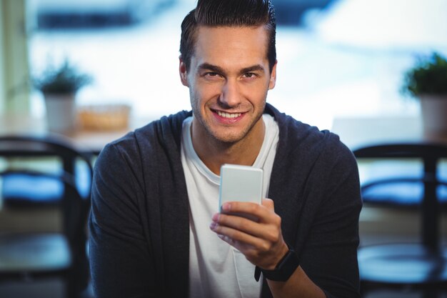 Smiling man using mobile phone in cafe