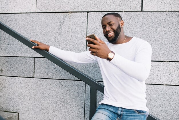 Smiling man using smartphone on staircase