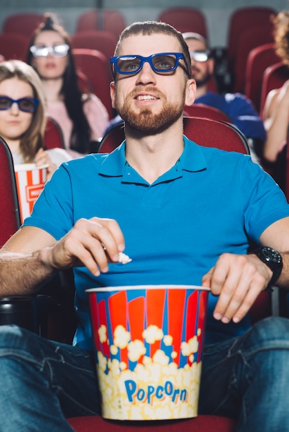 Foto gratuita uomo sorridente che guarda film nel cinema