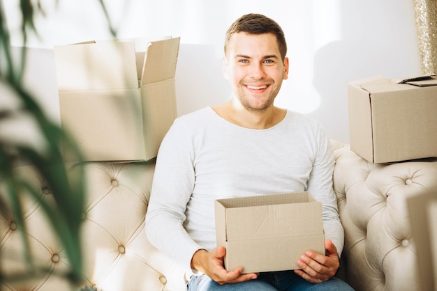 Uomo sorridente con scatola in appartamento