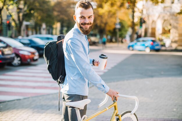 Smiling man with cup and bicycle