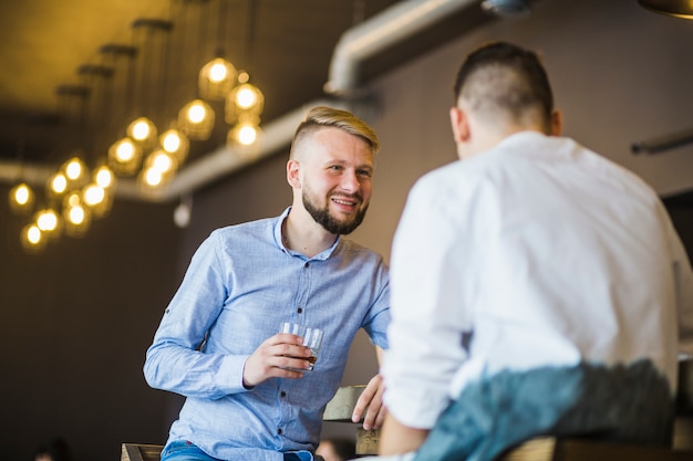 レストランで飲み物を楽しむ彼の友人と笑顔の男