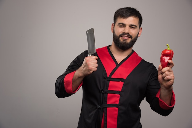 Smiling man with knife and red pepper.