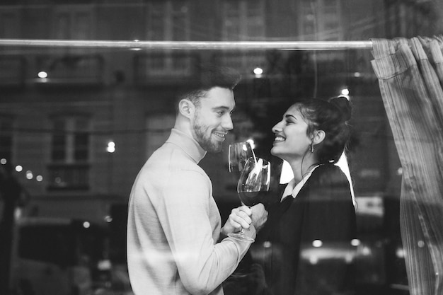Smiling man and woman holding glasses of wine in restaurant