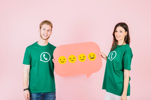 Smiling man and woman holding speech bubble with various type of emoticons