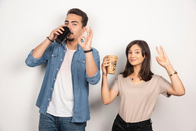 Smiling man and woman with cups of coffee. 