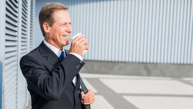 Smiling mature businessman drinking coffee at outdoors