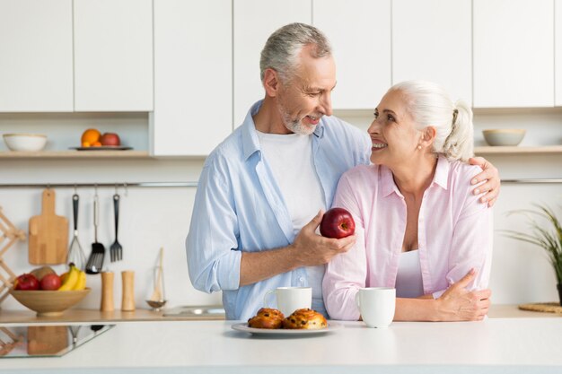 台所で立っている笑顔の成熟した愛情のあるカップル家族