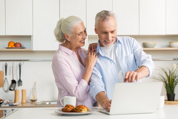 Smiling mature loving couple family using laptop computer