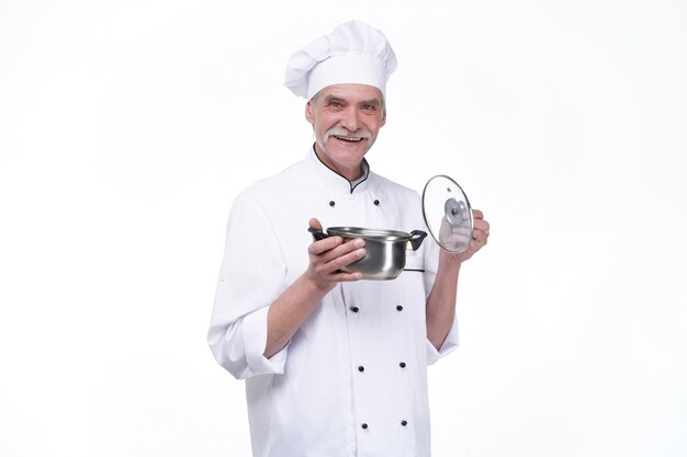 Smiling mature male chef with metal bowl in hands on white wall