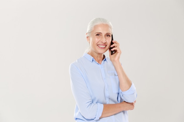 Smiling mature woman talking on smartphone isolated