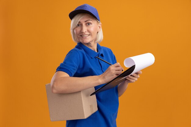 Smiling middle-aged blonde delivery woman in blue uniform and cap 