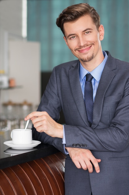 Smiling Middle-aged Businessman Stirring Coffee