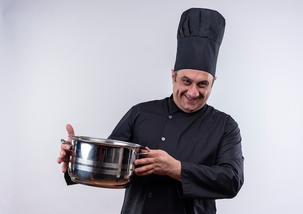 Smiling middle-aged male cook in chef uniform holding pot with copy space