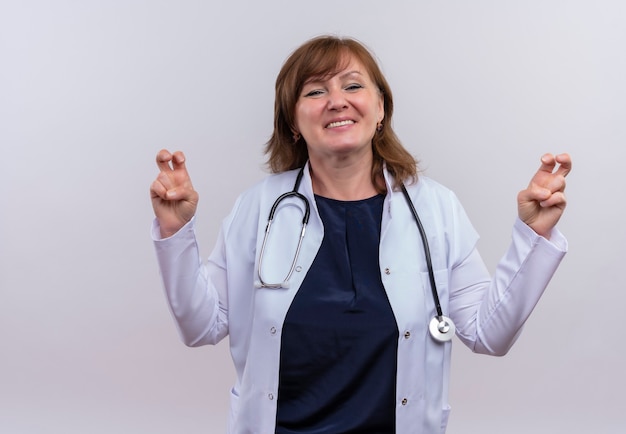 Foto gratuita sorridente donna di mezza età medico indossando abito medico e stetoscopio facendo citazioni gesto sulla parete bianca isolata con lo spazio della copia