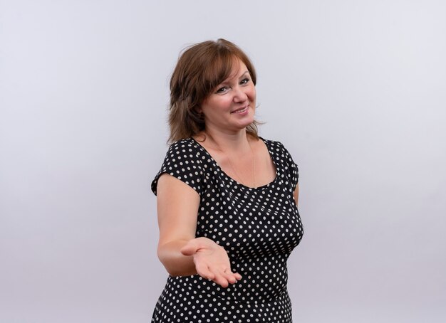 smiling middle-aged woman showing empty hand on isolated white wall