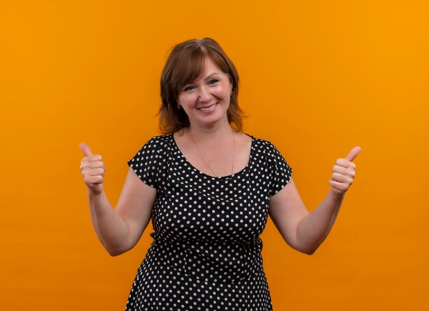 smiling middle-aged woman showing thumbs up on isolated orange wall