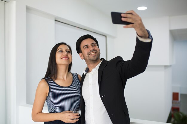 Smiling mixed race businessman photographing with colleague