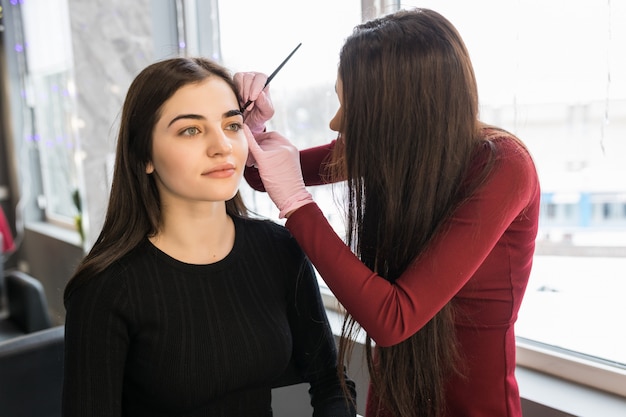 Smiling model is doing eyebrow painting procedure