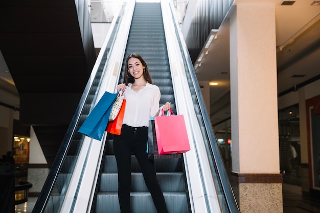 Smiling model with bags on escalator