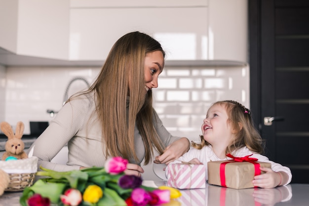 Smiling mom giving present to her daughter on her birthday