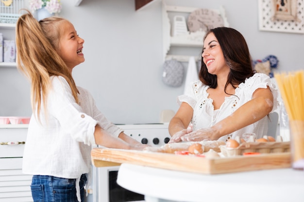 Free photo smiling mother and daughter cooking