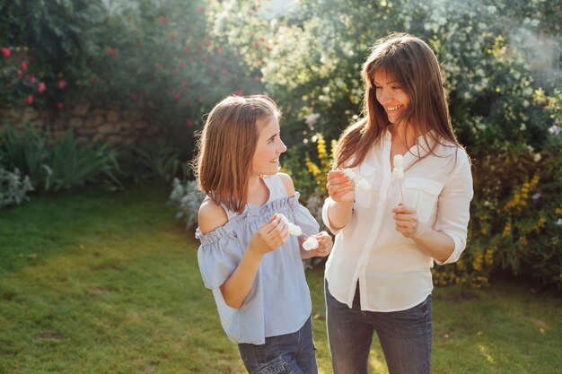 Smiling mother and daughter holding marshmallow skewer and looking at each other in park