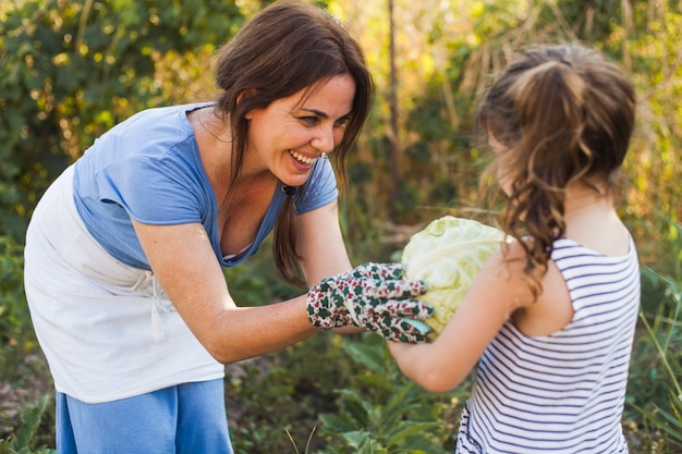 Free photo smiling mother giving cabbage to her daughter