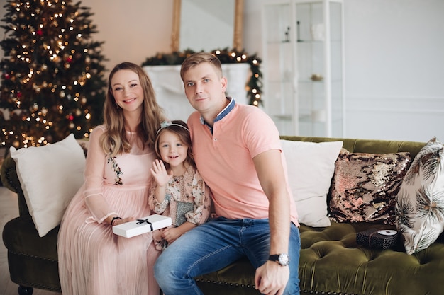 Smiling mother giving gift box to cute little daughter during christmas event dinner feeling love