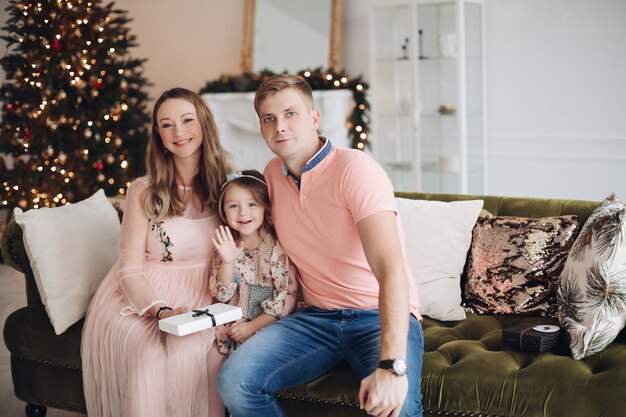 Smiling mother giving gift box to cute little daughter during christmas event dinner feeling love