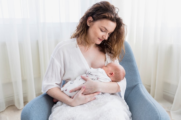 Smiling mother with her baby sitting on arm chair